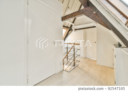 Closed white door of room located near framed pictures and stylish lamp on top of stairway at home 92547105