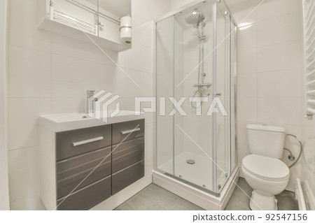 Tiled shower cabin with glass door located near sink and mirror in light restroom in contemporary apartment Tiled shower cabin with glass door located near sink and mirror in light restroom in contemporary apartment 92547156