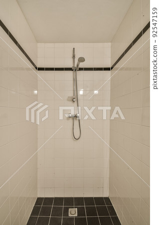 Flush toilet located between sink and shower in small tiled bathroom of contemporary apartment Flush toilet located between sink and shower in small tiled bathroom of contemporary apartment 92547159