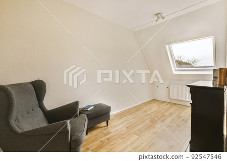 Interior of spacious apartment room on attic of building furnished with gray sofa and dining table with ladder leading upstairs Interior of spacious apartment room on attic of building furnished with gray sofa and dining table with ladder leading upstairs 92547546