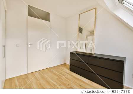 Interior of spacious apartment room on attic of building furnished with gray sofa and dining table with ladder leading upstairs Interior of spacious apartment room on attic of building furnished with gray sofa and dining table with ladder leading upstairs 92547578