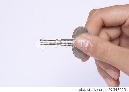 Woman hand holding key making door opening motion on white background Woman hand holding key making door opening motion on white background 92547623