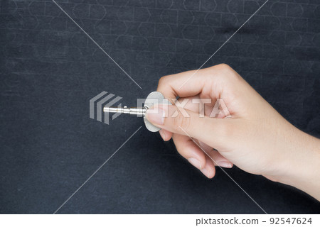 Woman hand holding key making door opening motion on black background Woman hand holding key making door opening motion on black background 92547624