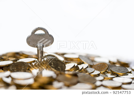 A key in a pile of gold coins 92547753