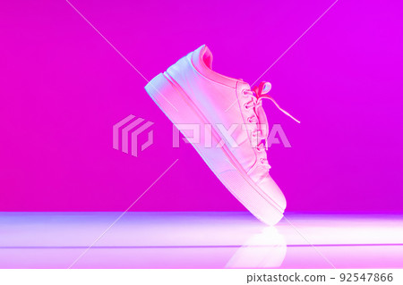 Unisex sports shoes, sneakers isolated over purple neon background. Urban city fashion, fitness, sport, training concept. Unisex sports shoes, sneakers isolated over purple neon background. Urban city fashion, fitness, sport, training concept. 92547866