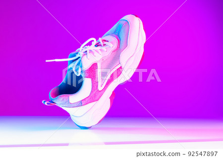 One sports shoe isolated over neoned background. Urban city fashion, fitness, sport, training concept. One sports shoe isolated over neoned background. Urban city fashion, fitness, sport, training concept. 92547897