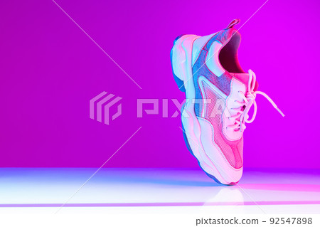 One sports shoe isolated over neoned background. Urban city fashion, fitness, sport, training concept. 92547898
