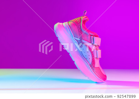 One sports shoe isolated over neoned background. Urban city fashion, fitness, sport, training concept. 92547899