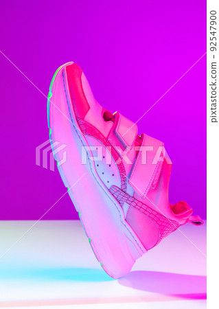 Unisex sports shoes, sneakers isolated over purple neon background. Urban city fashion, fitness, sport, training concept. Unisex sports shoes, sneakers isolated over purple neon background. Urban city fashion, fitness, sport, training concept. 92547900