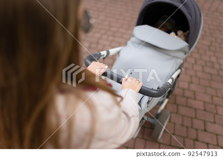 Mom's hands on the baby stroller 92547913