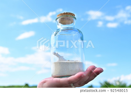 Hand holding a glass bottle containing coral sand and coral SDGs Environmental problems Image 92548015