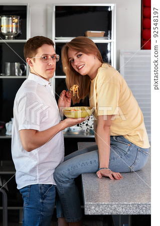 Smiling loving husband feeding wife, young couple enjoying tender moment, romantic date, having fun, eating japanese cuisine, happy family spending free weekend in modern kitchen 92548197