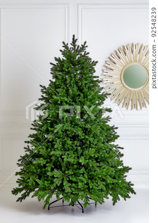 Artificial Christmas green tree without decorations on a metal stand isolated on a white background. Artificial Christmas green tree without decorations on a metal stand isolated on a white background. 92548239