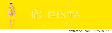 Halloween minimal decorations, composition with spooky skeleton monster isolated on yellow background. Halloween celebration trick or treat concept. Flat lay top view copy space banner 92548314