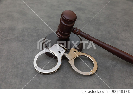 Law theme. Court of law trial in session. Judge gavel handcuffs on grey table in lawyer office or court session. Mallet of judge on concrete stone grey background. Justice human rights concept Law theme. Court of law trial in session. Judge gavel handcuffs on grey table in lawyer office or court session. Mallet of judge on concrete stone grey background. Justice human rights concept 92548328