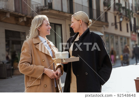 Two elegant ladies having a conversation outdoors Two elegant ladies having a conversation outdoors 92548648