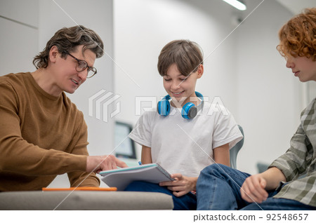 Teacher in eyeglasses explaining something to his students Teacher in eyeglasses explaining something to his students 92548657