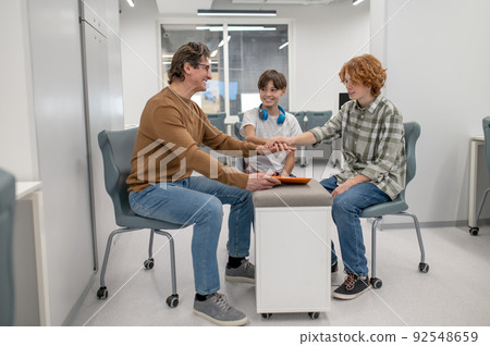 Teacher in eyeglasses explaining something to his students Teacher in eyeglasses explaining something to his students 92548659