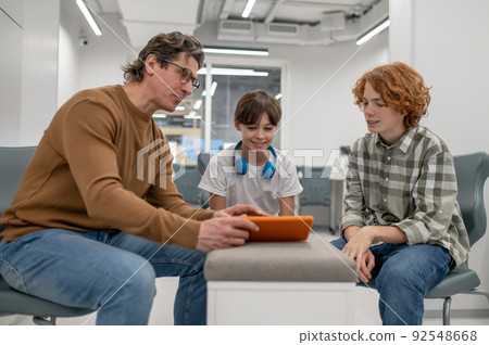 Teacher in eyeglasses explaining something to his students Teacher in eyeglasses explaining something to his students 92548668