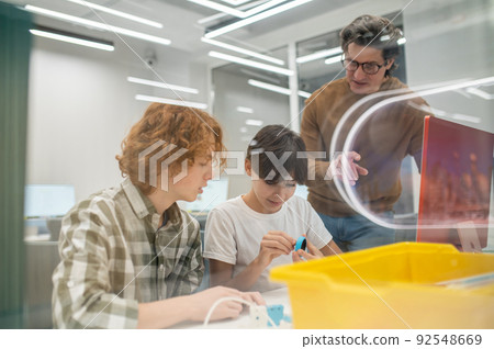 Teacher in eyeglasses explaining something to his students 92548669