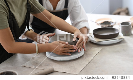 Young asian woman and mature woman molding clay, enjoy making handcrafted ceramics in pottery workshop 92548884
