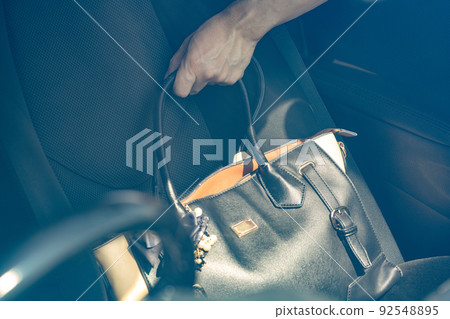 Hand to pull out the bag from the passenger seat of the car Hand to pull out the bag from the passenger seat of the car 92548895