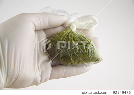 man in white medical gloves holds powder carcinogenic chewing tobacco (nas, nasvay, dip, snus) from Tajikistan, in a closed bag man in white medical gloves holds powder carcinogenic chewing tobacco (nas, nasvay, dip, snus) from Tajikistan, in a closed bag 92549476