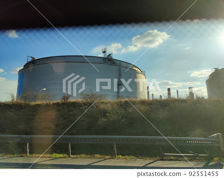 Oil storage tank terminal and tanker, petrol industrial zone shot from a moving car 92551455