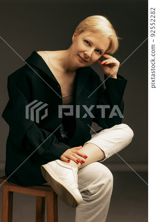 Portrait of beautiful middle-aged woman in stylish casual black and white outfit posing isolated over dark background 92552282