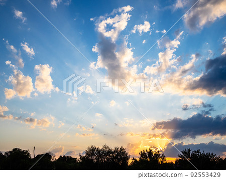 rays of setting sun in dark blue sky in evening rays of setting sun in dark blue sky in evening 92553429