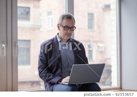 Serious puzzled businessman looking at laptop Serious puzzled businessman looking at laptop 92553657