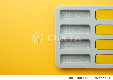 Natural beeswax. Molded bars of beeswax in a silicone mold on a yellow background. Beekeeping products. Copy space. Natural beeswax. Molded bars of beeswax in a silicone mold on a yellow background. Beekeeping products. Copy space. 92553693