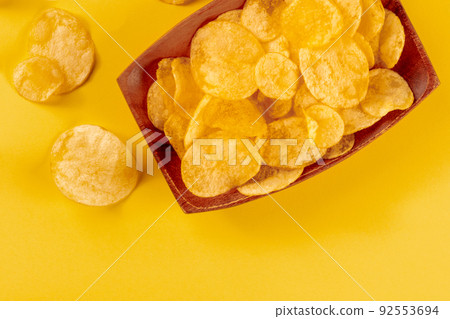 Potato chips or crisps in a bowl, shot from the top on a yellow background 92553694