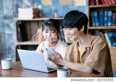 Couple using laptop and smartphone Couple using laptop and smartphone 92553850