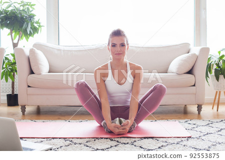 Young woman at home stretching out after exercising Young woman at home stretching out after exercising 92553875
