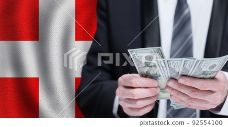 Hands holding dollar money on flag of Denmark Hands holding dollar money on flag of Denmark 92554100