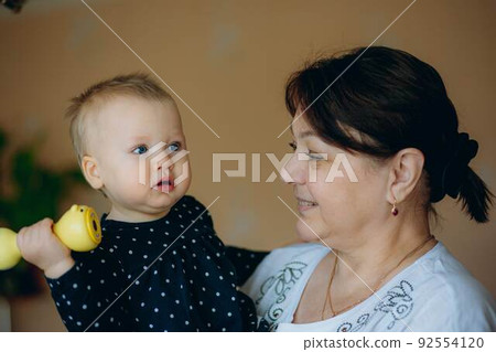 little caucasian baby girl and grandmother. woman hugging granddaugher with love 92554120