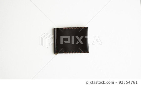Brown men's money clip handmade leather wallet. Empty money clip wallet with a two pockets for cards lies on a white table. Selective focus, copy space. Brown men's money clip handmade leather wallet. Empty money clip wallet with a two pockets for cards lies on a white table. Selective focus, copy space. 92554761