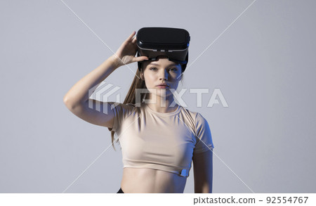 Portrait of young woman wearing a virtual reality headset goggles and ready to play a game with a friends. Future technology concept. 92554767