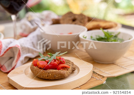 Tipical summer south Italian appetizer Friselle with cherry tomatoes, oil and rucola served outdoor Tipical summer south Italian appetizer Friselle with cherry tomatoes, oil and rucola served outdoor 92554854