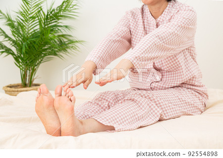 Middle woman wearing pajamas and stretching with a futon 92554898