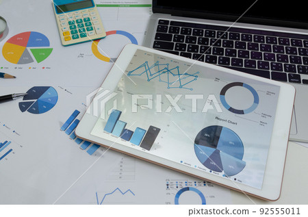Document paperwork graph and chart at tablet with computer laptop and pen. Business finance analysis report marketing and information investment accounting at office digital technology concept. 92555011