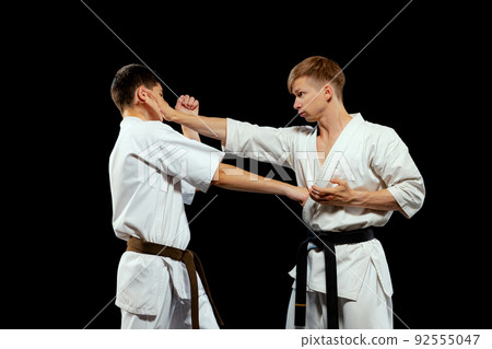 Dynamic portrait of male karate-do fighters in sports uniform training together isolated on black background. Concept of sport, education, skills, martial arts, health 92555047