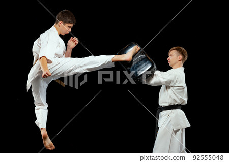 Dynamic portrait of male karate-do fighters in sports uniform training together isolated on black background. Concept of sport, education, skills, martial arts, health 92555048