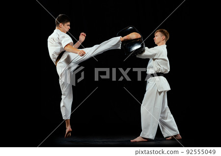 Dynamic portrait of male karate-do fighters in sports uniform training together isolated on black background. Concept of sport, education, skills, martial arts, health 92555049