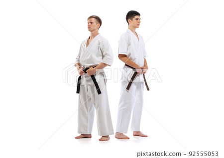 Two athletes, karate-do fighters in doboks practicing karate isolated on white background. Concept of sport, education, skills, martial arts, healthy lifestyle 92555053