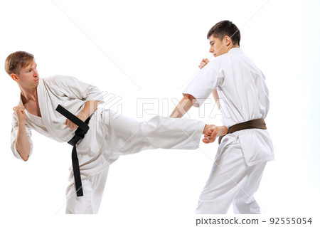 Two athletes, karate-do fighters in doboks practicing karate isolated on white background. Concept of sport, education, skills, martial arts, healthy lifestyle 92555054