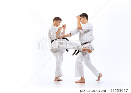 Two athletes, karate-do fighters in doboks practicing karate isolated on white background. Concept of sport, education, skills, martial arts, healthy lifestyle Two athletes, karate-do fighters in doboks practicing karate isolated on white background. Concept of sport, education, skills, martial arts, healthy lifestyle 92555057