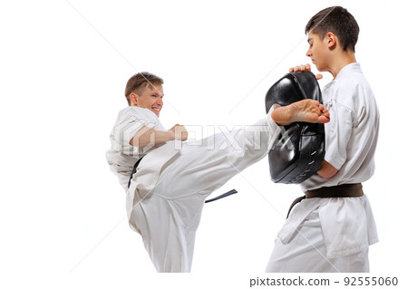 Two athletes, karate-do fighters in doboks practicing karate isolated on white background. Concept of sport, education, skills, martial arts, healthy lifestyle Two athletes, karate-do fighters in doboks practicing karate isolated on white background. Concept of sport, education, skills, martial arts, healthy lifestyle 92555060