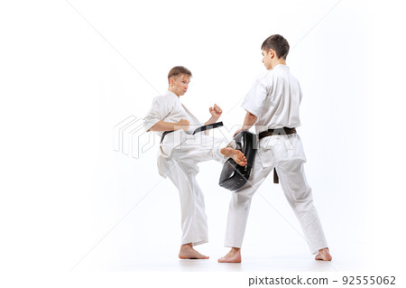 Two athletes, karate-do fighters in doboks practicing karate isolated on white background. Concept of sport, education, skills, martial arts, healthy lifestyle 92555062